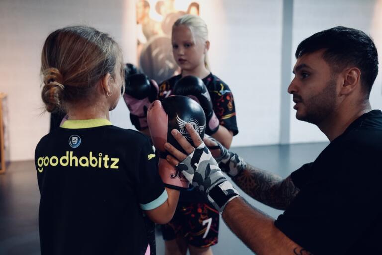 Trainer Bijan van Thaiboxing Center Venlo geeft uitleg over basistechnieken aan kinderen tijdens de kickboksles