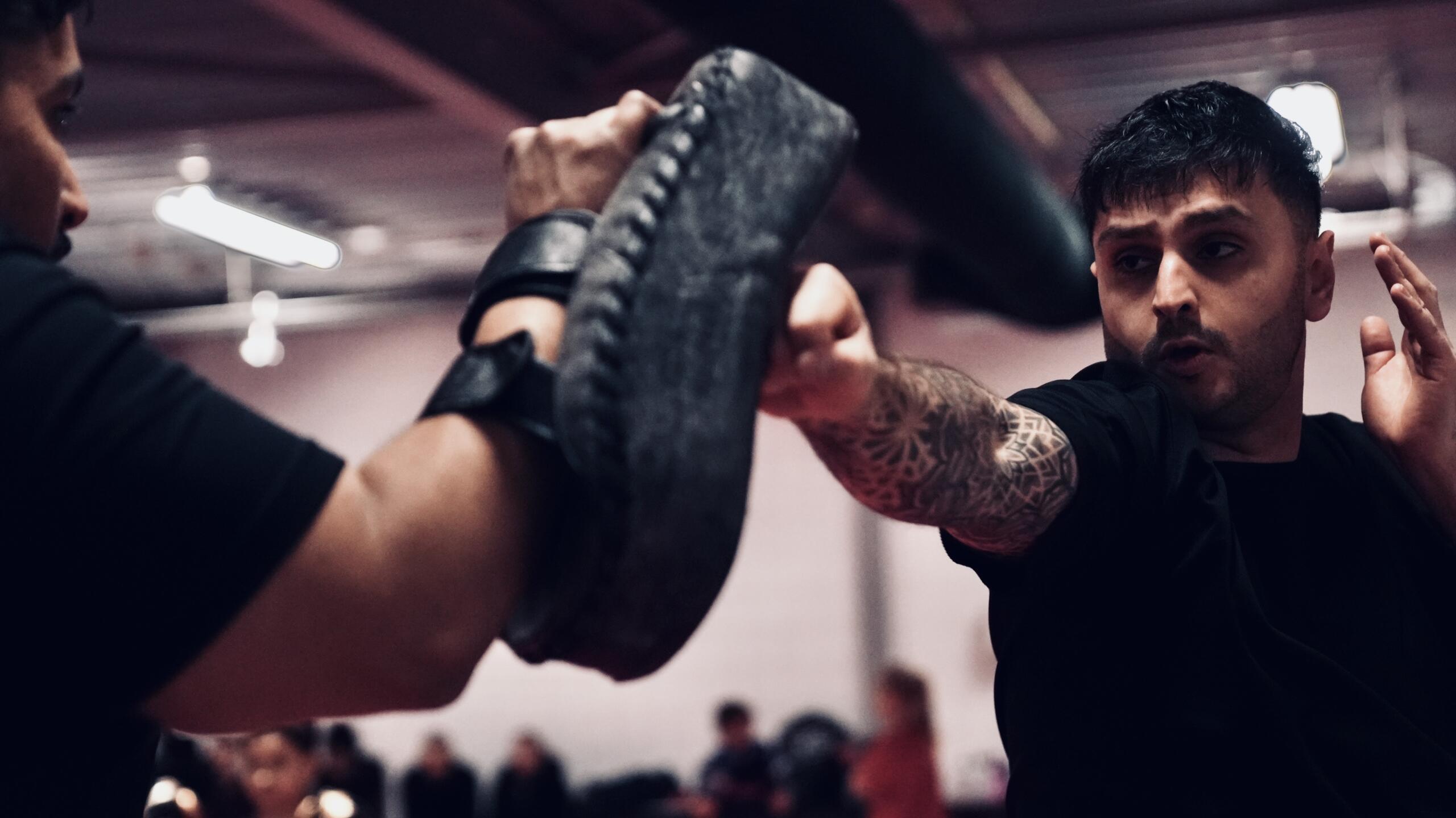 Bijan voert een combinatie uit op de pads tijdens de training voor ervaren vechtsporters